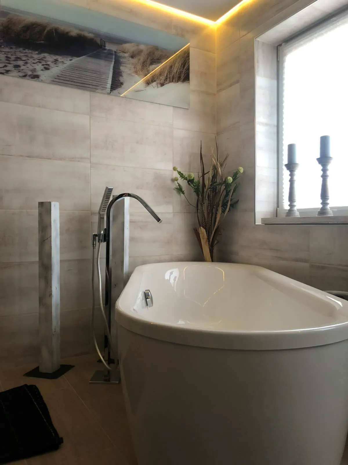 Badezimmer mit freistehender Wanne und warmer, umlaufender Lichtvoute