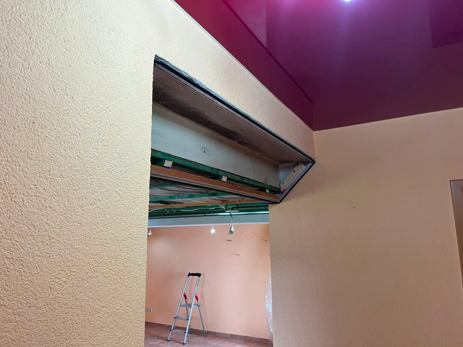 Magentafarbene Lackfläche als Absatz in einer weißen Decke