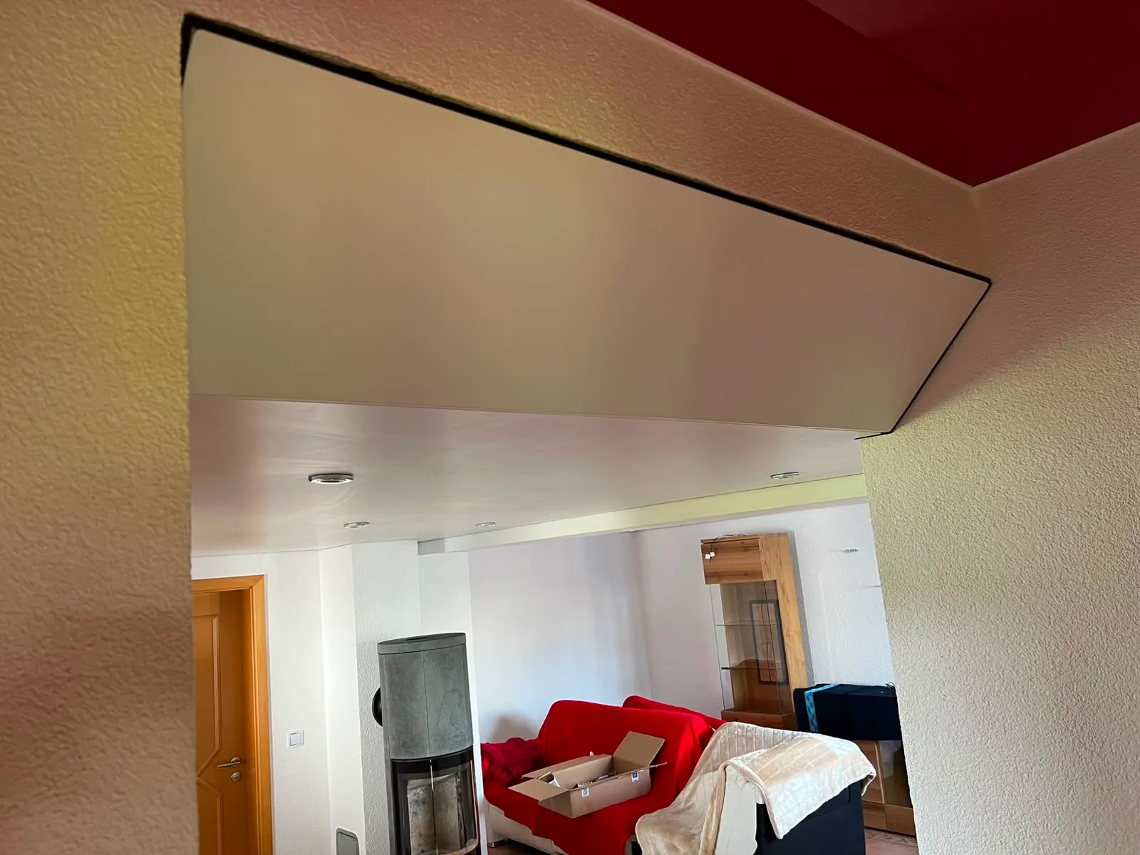 Roter Lackabsatz an der Decke über einem hellen Wohnraum
