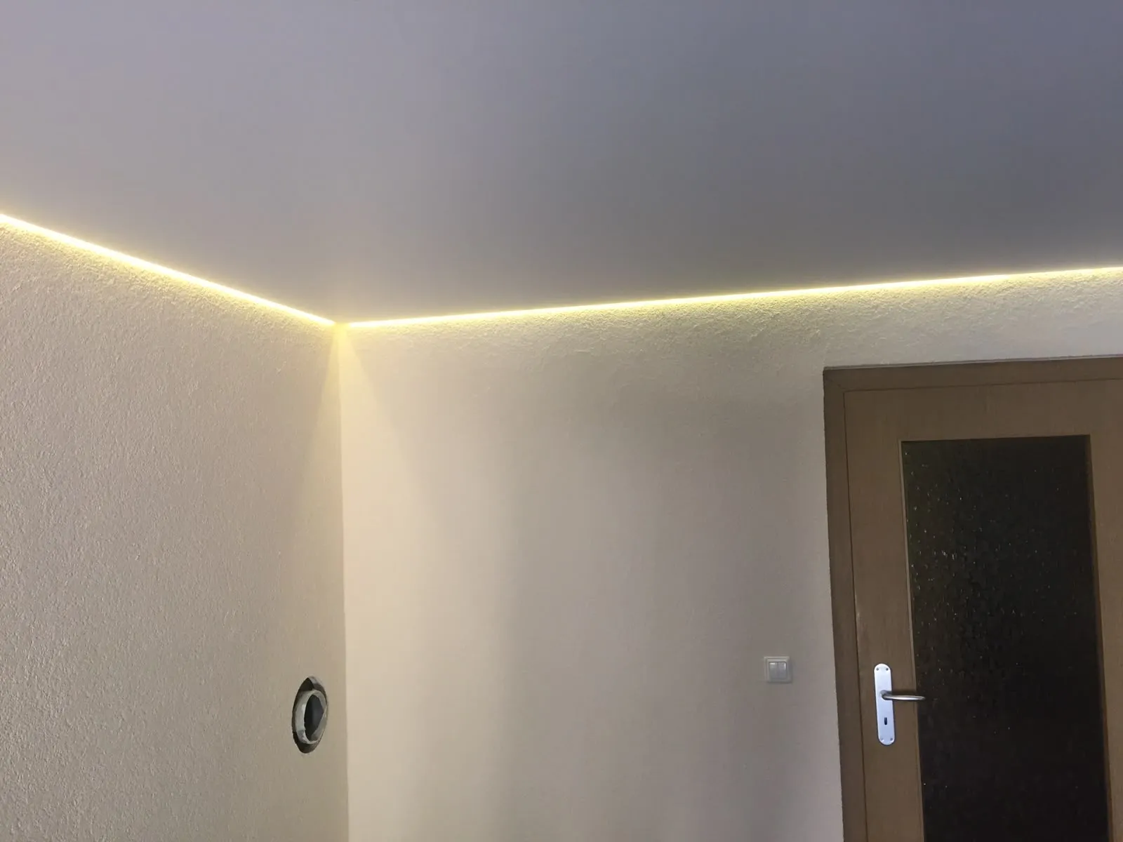 Umlaufende LED-Linie entlang der Deckenkante neben einer Zimmertür