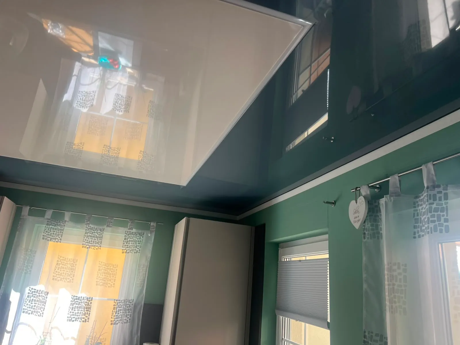 Dunkle Hochglanzdecke mit leuchtendem Lichtpanel über der Küchenzeile