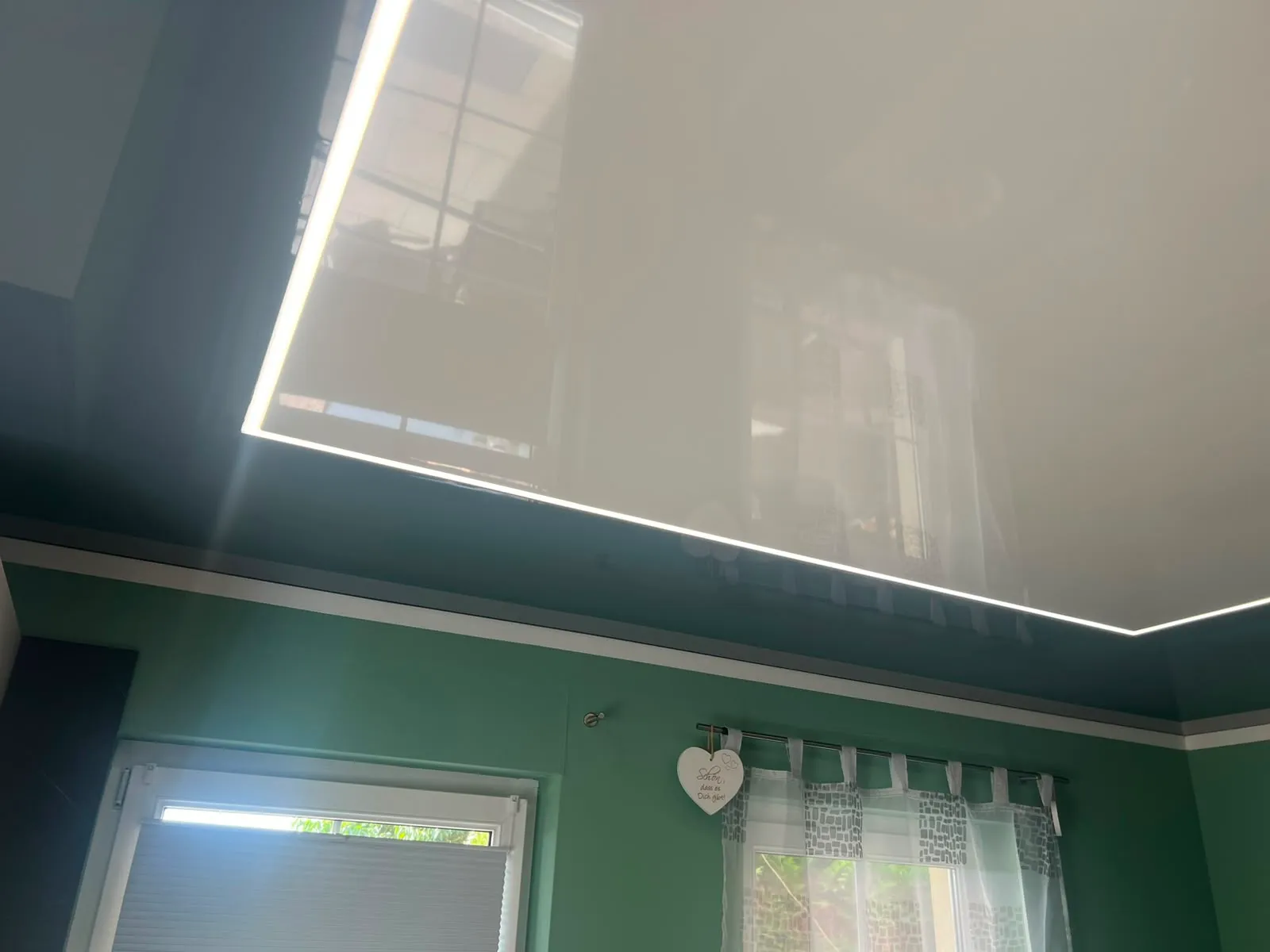 Küche mit grüner Wand unter der dunklen Hochglanzdecke