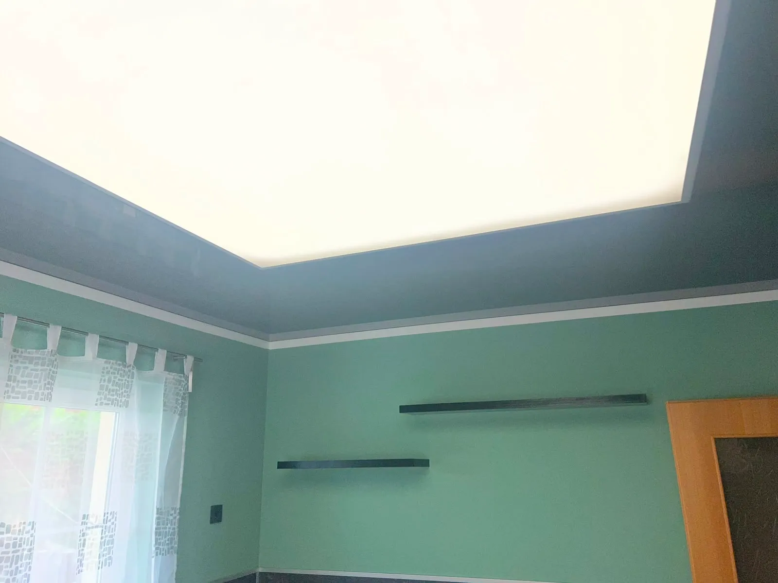 Dunkle Hochglanzdecke mit leuchtendem weißem Lichtpanel und umlaufender LED-Linie