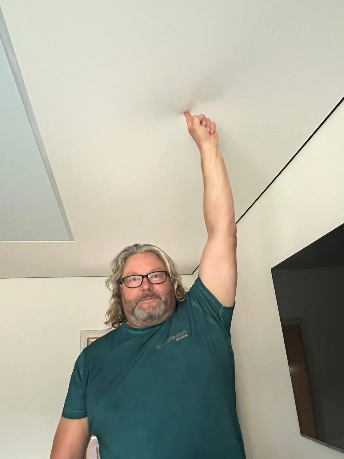 Mike Witczak zeigt auf die von ihm montierte Spanndecke