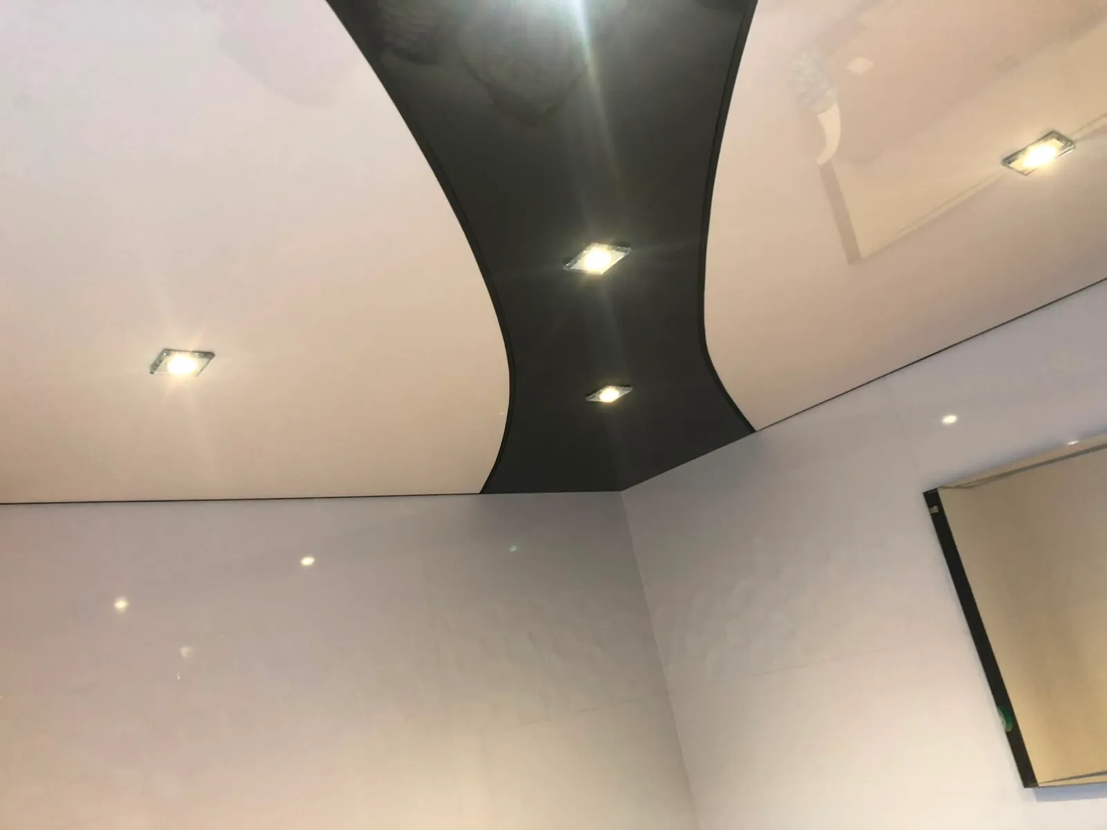 Weiße Decke mit geschwungenem schwarzem Trennprofil und quadratischen Spots