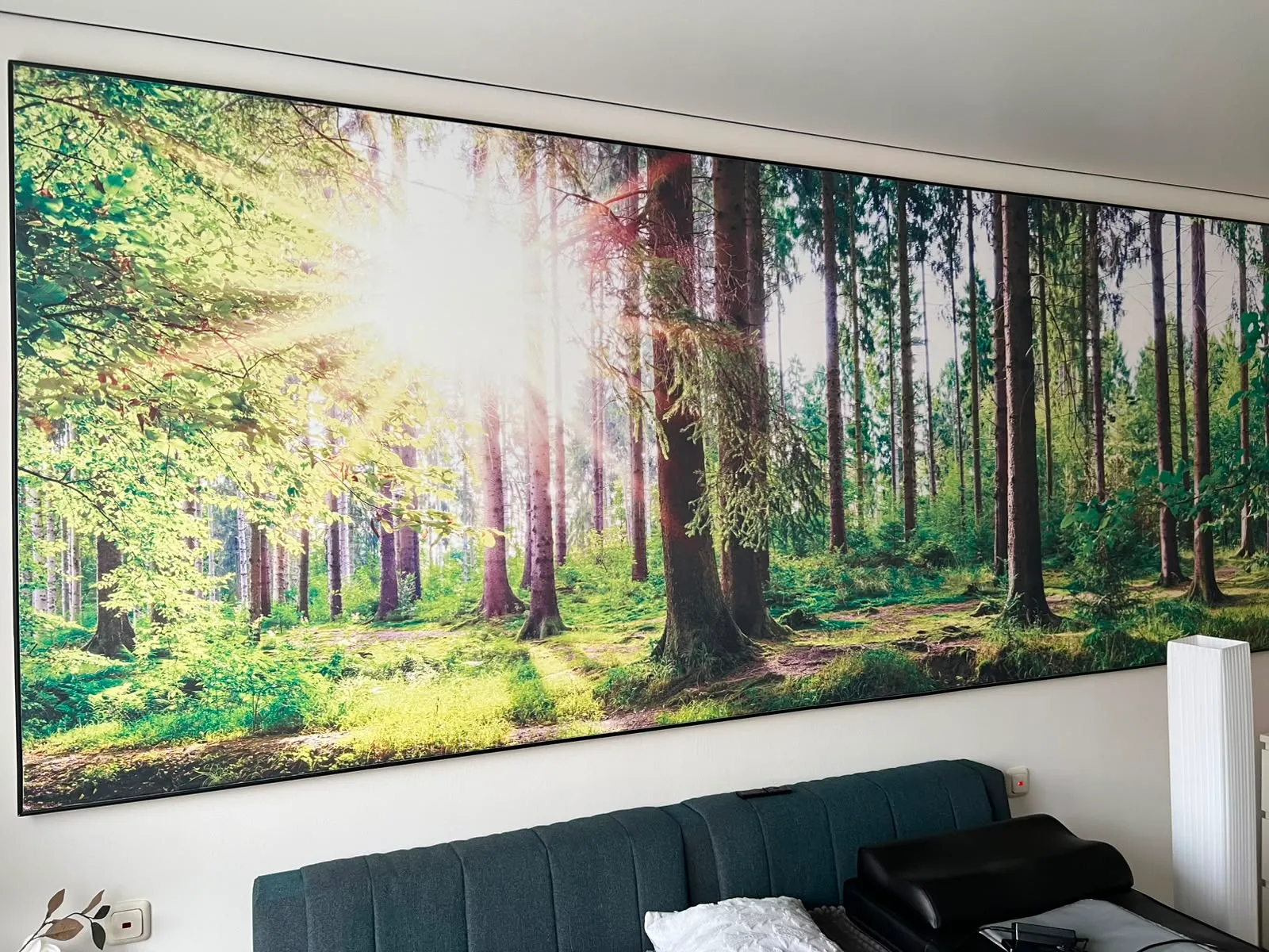 Bedrucktes Waldmotiv als großflächige Wandbespannung über einem Bett