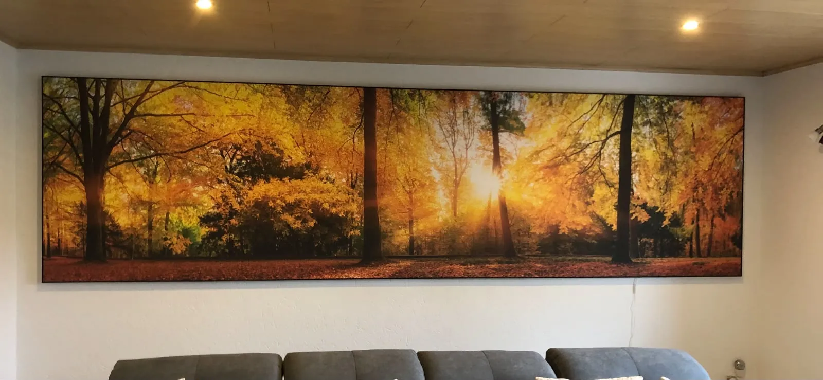 Bedrucktes Wandpaneel mit herbstlichem Waldmotiv über einer Sitzecke