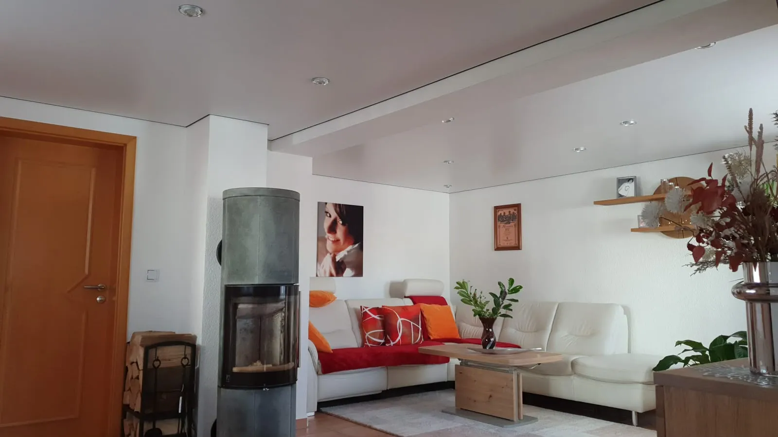 Wohnzimmer mit weißer Satindecke, Kaminofen und Sitzgruppe
